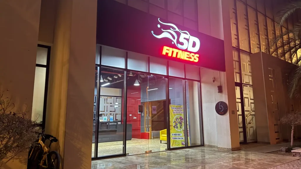 5D Fitness gym entrance in Muscat, Oman with modern glass facade and illuminated fitness sign