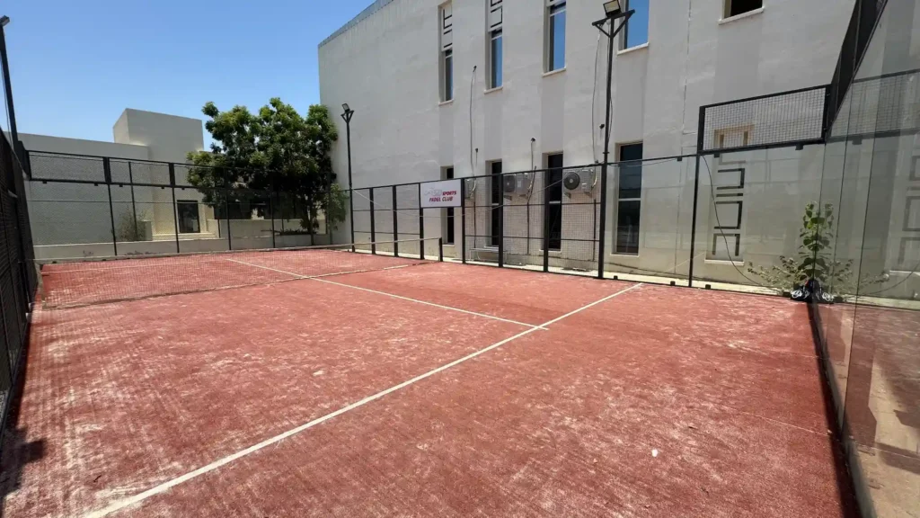 Outdoor padel court in Muscat, Oman with glass walls, court lines, and sports club facilities for training and matches