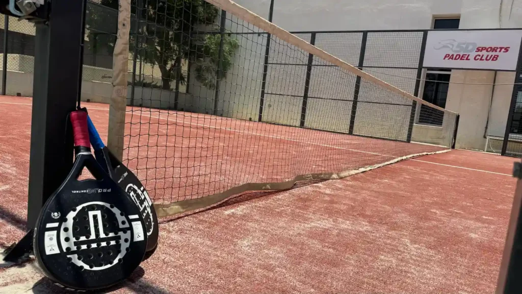 Padel racket beside the net on an outdoor padel court in Muscat, Oman at 5D Sports Padel Club