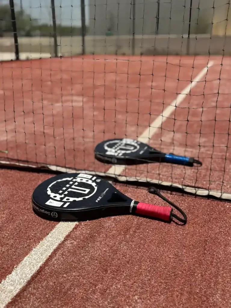 Padel rackets on an outdoor padel court in Muscat, Oman with net and court lines for sports training